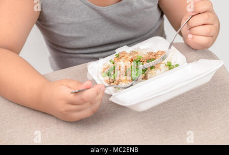 Beleibte Fat Boy Essen gebratener Reis in Schaumstoff box auf weißem Hintergrund, Junk Food und gefährlich für die Gesundheit Stockfoto