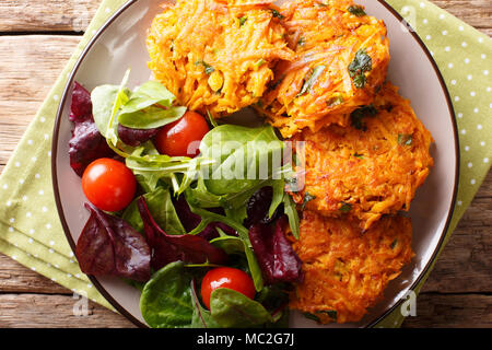 Frisch knusprige Krapfen von Süßkartoffel und frisches Gemüse Salat auf einen Teller close-up gemacht. horizontal oben Ansicht von oben Stockfoto