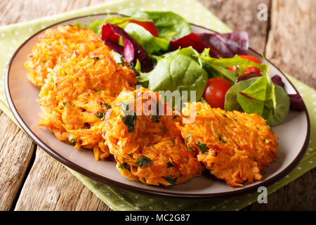 Frisch knusprige Krapfen von Süßkartoffel und frisches Gemüse Salat auf einen Teller close-up gemacht. Horizontale Stockfoto