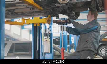 Mechaniker schraubt Detail des Autos in der Motorhaube - KFZ-Service Reparatur, Nahaufnahme Stockfoto