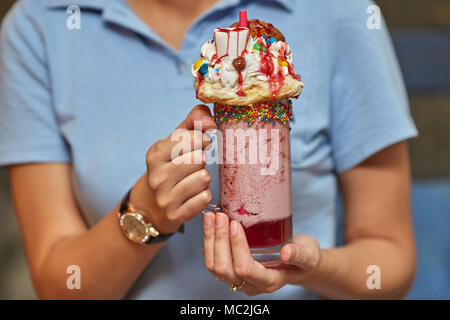 Hans mit Marshmallow Milch shake Cocktail mit Schlagsahne, Cookies, Muffins, behandelt Stockfoto