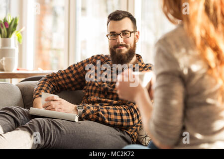 Schöner Mann im Gespräch mit seiner Frau beim Tee trinken zusammen zu Hause Stockfoto