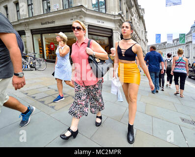 London, England, UK. Frauen in der Regent Street - kontrastierende Mode-stile. Junge Frau in Kunststoff/Leder Rock Stockfoto