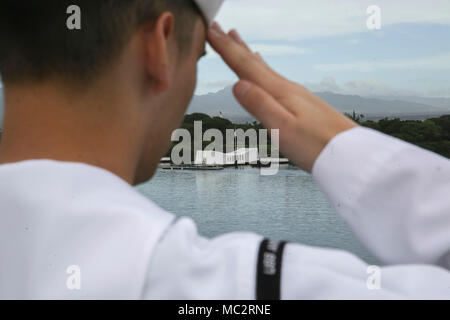 PEARL HARBOR NAVAL BASE, HI - ein Seemann mit dem Amerika Amphibious Ready Gruppe an Bord amphibisches Schiff USS America (LHA 6) begrüßt, da sie das USS Arizona Memorial verlassen, Jan. 25, 2018. Manning der Schienen ist ein Naval Tradition jede Bereitstellung von Schiff führt und ist eine Methode der ehrenkompanie oder Rendering Ehren durch Marineschiffe verwendet. Die 15. MEU und Amerika ARG sind derzeit auf eine Routine für sieben Monate, um die Bereitstellung zu den USA 3., 5. und 7 Flotte Bereiche des Betriebes als Reaktion auf Krisen und Kontingenz Kraft eingesetzt. (U.S. Marine Corps Foto von Cpl. Timothy Valero) Stockfoto