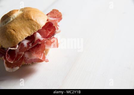 Typisch italienisches Einbau als Sandwitch mit coppa (in Piacenza, Nord Italien) auf einem weißen Tisch, wobei ein Schwerpunkt auf der linken Seite Stockfoto