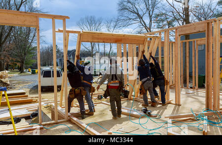 Bauarbeiter mit Bolzenschußgeräten auf Holz Gebäude Rahmen gegen Haus bauen Stockfoto