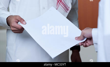 Saudische Geschäftsmann Übergabe eines Dokuments an einen anderen Mitarbeiter. Stockfoto