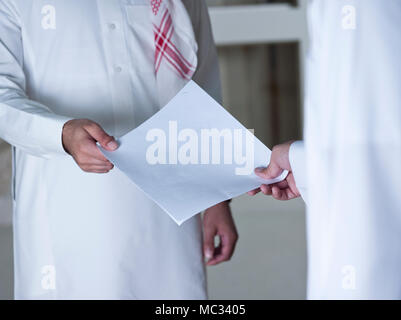 Saudische Geschäftsmann Übergabe eines Dokuments an einen anderen Mitarbeiter. Stockfoto