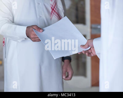 Saudische Geschäftsmann Übergabe eines Dokuments an einen anderen Mitarbeiter. Stockfoto