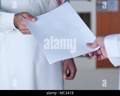 Saudische Geschäftsmann Übergabe eines Dokuments an einen anderen Mitarbeiter. Stockfoto