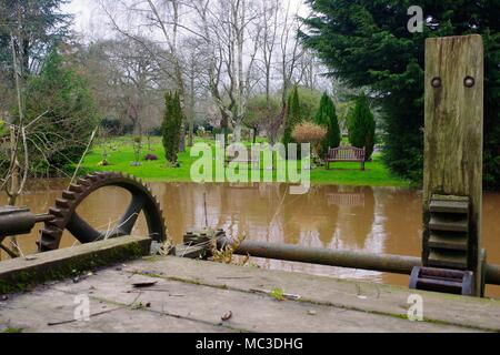 Gräfin Wehr Mühle Gewaehrleistung, viktorianischen Schleuse Tor und Exeter & Devon Krematorium Gärten. River Exe in der Flut. UK. April, 2018. Stockfoto