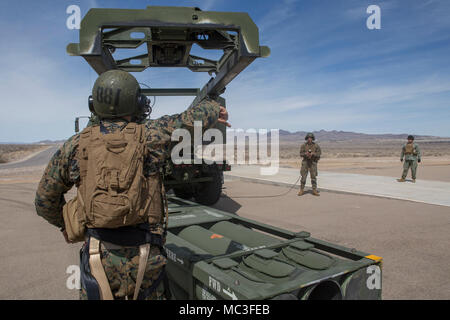 Marine Corps Sgt. Jeffery Hale, ein Launcher Chief mit Kilo. Akku, 2. Bataillon, 14 Marine Regiment, Signale für Cpl. Kyle Thompson, ein Gunner mit Kilo Batterien, das Hebezeug zu senken auf einer M142 High Mobility Artillery Rocket System (HIMARS) Raketen pods abzuholen, in Dugway Proving Grounds, Utah, 30. März 2018. Marines von Kilo Batterie flogen von Fort Campbell, Ky., Dugway, wo Sie entladen und feuerte vier HIMARS Raketen, die eine einzigartige Fähigkeit, die kommandeure mehr Optionen mit Bedrohungen zu begegnen, wenn die anderen Optionen nicht angemessen sind. Stockfoto