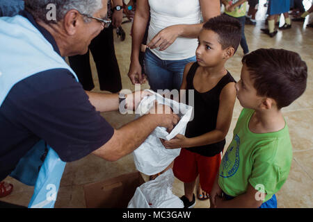 HUMACAO, Puerto Rico, 12. Januar 2018 - ein Junge bekommt ein Paar neue Schuhe ab einer Spende von FEMA-Mitarbeiter und der Gemeinde organisiert. Über 150 Paar Schuhe der Kinder waren zum Hurrikan Maria Überlebenden auf der Veranstaltung gegeben. Stockfoto