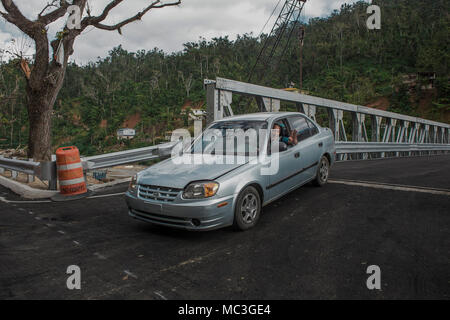 Utuado, Puerto Rico. März 13, 2018 -- Eine glückliche Bewohner von Río Abajo ist einer der ersten sein Auto über die neue Brücke in seiner Gemeinschaft zu fahren. Nach dem Hurrikan María durch die Insel Riss, der starke Regen brach die bisherige Brücke verlassen mehr als 25 Familien isoliert. Heute, dank der Anstrengungen der örtlichen, Landes- und Bundesbehörden, hat die Gemeinschaft eine neue Brücke. Stockfoto