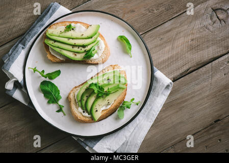 Avocado Sandwiches mit Frischkäse - in Scheiben Avocado auf geröstetem Brot für gesundes Frühstück oder einen Snack. Stockfoto
