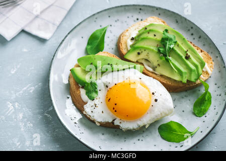 Avocado Sandwich mit Spiegelei - in Scheiben Avocado und Ei auf Toast mit Rucola für gesundes Frühstück oder einen Snack. Stockfoto