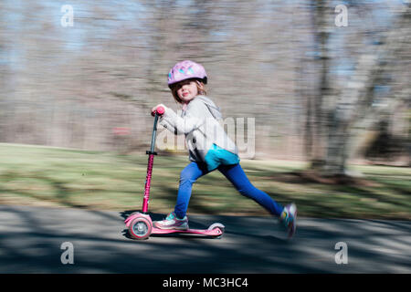 Schuß von kleinen Mädchen reiten ein scooter geschwenkt Stockfoto