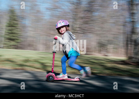 Schuß von kleinen Mädchen reiten ein scooter geschwenkt Stockfoto