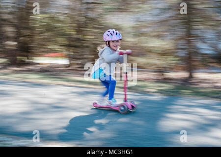 Schuß von kleinen Mädchen reiten ein scooter geschwenkt Stockfoto