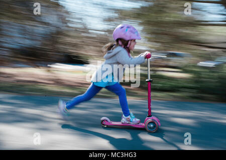 Schuß von kleinen Mädchen reiten ein scooter geschwenkt Stockfoto