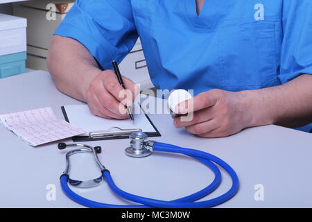Der Arzt hält einen Blister mit Pillen in die Hand und schreibt die Verordnung in den Arbeitsplatz hautnah. Arzneimittel verschreiben, eine zugelassene Apotheke, Behandlung von Krankheiten Stockfoto