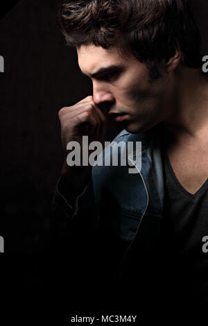 Denken schwere Depression charismatische Mann auf dunklen Schatten dramatisch hellen Hintergrund. Closeup Portrait. Kunst Stockfoto