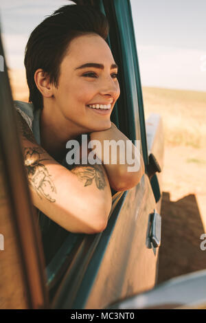 Frau mit Tattoos auf dem Arm aus dem Fenster ihres Autos. Frau genießen der Road Trip. Stockfoto