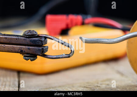 Zubehör in der Elektronik Werkstatt. Lötkolben, Zinn und andere Werkzeuge für Reparaturen von elektronischen Geräten erforderlich. Der dunkle Hintergrund. Stockfoto