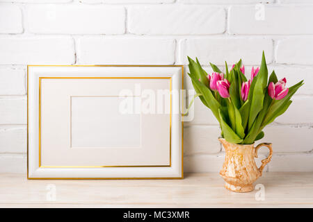 Gold Landschaft, frame Mockup mit hell magenta pink tulip Blumenstrauß in der goldenen Vase. Leeren Rahmen mock up für Präsentation Artwork. Templa Stockfoto