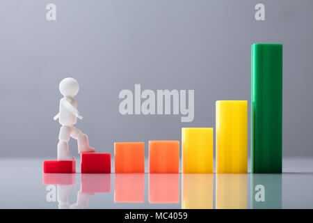 Menschliche Figur zu Fuß auf die bunten Business graph Vor grauem Hintergrund Stockfoto
