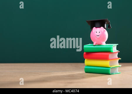 Close-up Sparschwein mit Graduierung hat über Mehrfarbige Abgelegte Bücher Stockfoto