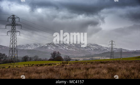 Eine stürmische Landschaft Dumfries und Galloway in Schottland mit Schnee auf den Bergen und Strommasten durch die Szene läuft Stockfoto