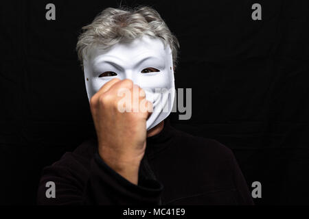 Grauhaariger Mann in anonymen Maske Holding eine Faust Stockfoto