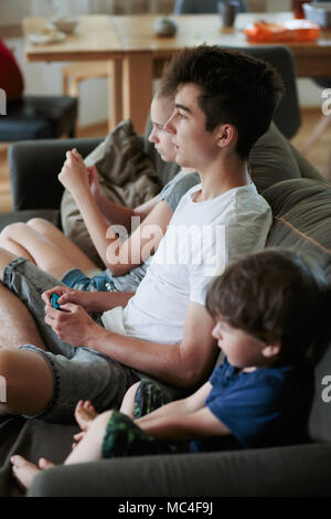 Konzentrierte sich Jungen und Mädchen spielen Videospiele auf dem Sofa zu Hause sitzen Stockfoto