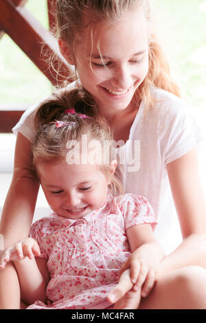 Junge Mädchen und ihre kleine Schwester Ausgabe Zeit zusammen auf Kitzeln und Lachen. Die Qualität der Zeit zu Hause. Stockfoto