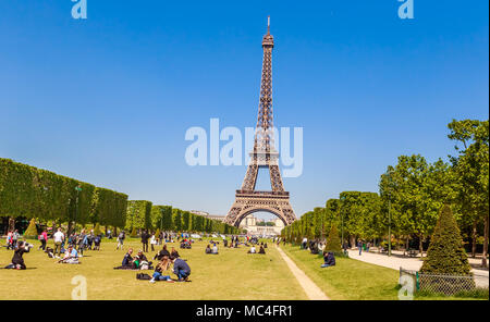Viele Menschen Entspannung und Spaß am Champ de Mars mit dem Eiffelturm im Hintergrund an einem sonnigen Tag. Paris, Frankreich Stockfoto