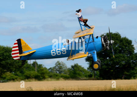 Sarah Niles wingwalking mit einer Boeing Stearman in Damyns Hall Flugplatz mit Kunstflug Taktik. Mädchen auf dem Flügel, Flügel zu Fuß. In der Nähe von Boden Stockfoto