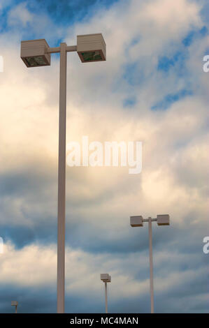 Zu Lichtmasten auf dem Parkplatz gegen einen bewölkten Himmel in der Schwarz-weiß-Foto mit Copyspace Stockfoto