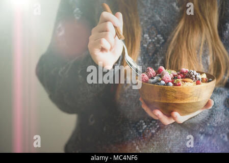 Frau Hände, die haferflocken Porridge mit gefrorenen Früchten, Mandeln in Houten. Banner. Gesundes Frühstück. Sauber Essen, detox Diät. Vegetarische, Raw, vegan Konzept Stockfoto