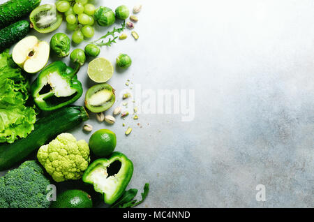 Organische grünes Gemüse und Früchte auf grauem Hintergrund. Kopieren Sie Raum, Flach, Ansicht von oben. Grüner Apfel, Salat, Zucchini, Gurke, Avocado, Kale, Kalk, Kiwi, Trauben, Bananen, Brokkoli Stockfoto