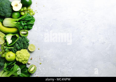 Organische grünes Gemüse und Früchte auf grauem Hintergrund. Kopieren Sie Raum, Flach, Ansicht von oben. Grüner Apfel, Salat, Zucchini, Gurke, Avocado, Kale, Kalk, Kiwi, Trauben, Bananen, Brokkoli Stockfoto