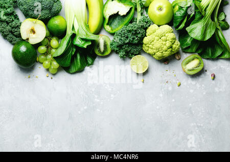 Organische grünes Gemüse und Früchte auf grauem Hintergrund. Kopieren Sie Raum, Flach, Ansicht von oben. Grüner Apfel, Salat, Zucchini, Gurke, Avocado, Kale, Kalk, Kiwi, Trauben, Bananen, Brokkoli Stockfoto