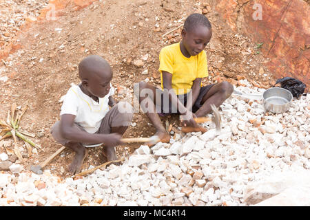 Lugazi, Uganda. 18. Juni 2017. Ugandische Jungen brechen Steine in kleine Platten für den Verkauf an ihre Vorarbeiter. Im Grunde Kinderarbeit. Stockfoto
