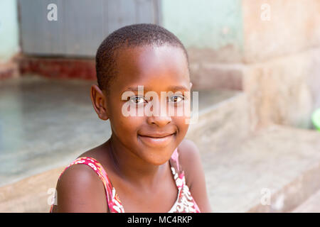 Lugazi, Uganda. 14. Mai 2017. Das Porträt einer wunderschönen ugandischen Mädchen sitzen auf der Treppe vor dem Haus. Stockfoto