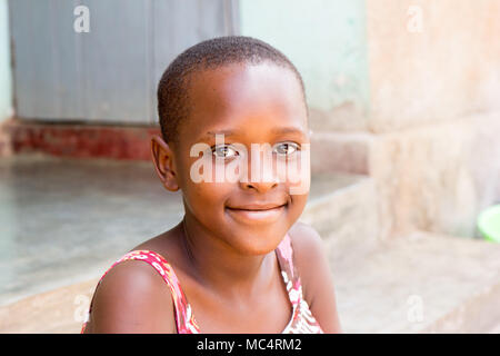 Lugazi, Uganda. 14. Mai 2017. Das Porträt einer wunderschönen ugandischen Mädchen sitzen auf der Treppe vor dem Haus. Stockfoto