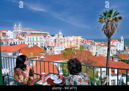 Zwei Frauen genießen Softdrink auf der sonnigen Terrasse mit Blick auf Lissabon Stockfoto