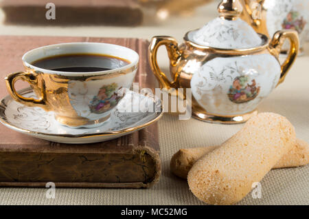 Espresso und Cookies Savoiardi auf einem Tisch mit einer Reihe von Vintage vergoldet Porzellan Geschirr aus dem 19. Jahrhundert Deutsche Bayern Stockfoto