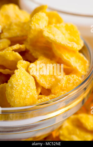 Zutaten für das Frühstück. Defokussierten und verschwommenes Bild der trockenen Cornflakes in einem transparenten Schüssel closeup mit geringer Tiefenschärfe Stockfoto