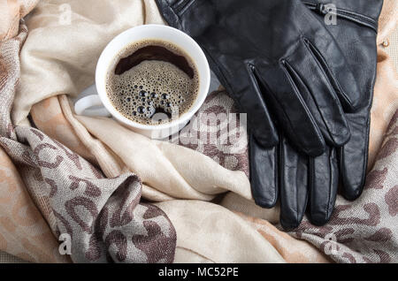 Weiße Tasse Espresso in den Falten der Frauen Schals und schwarze Lederhandschuhe Stockfoto