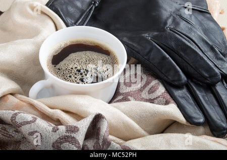 Weiße Tasse Espresso in den Falten der Frauen Schals und schwarze Lederhandschuhe Stockfoto